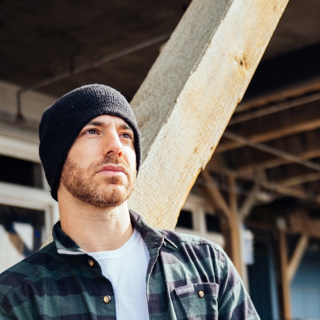 A man wearing a beanie and a plaid shirt.