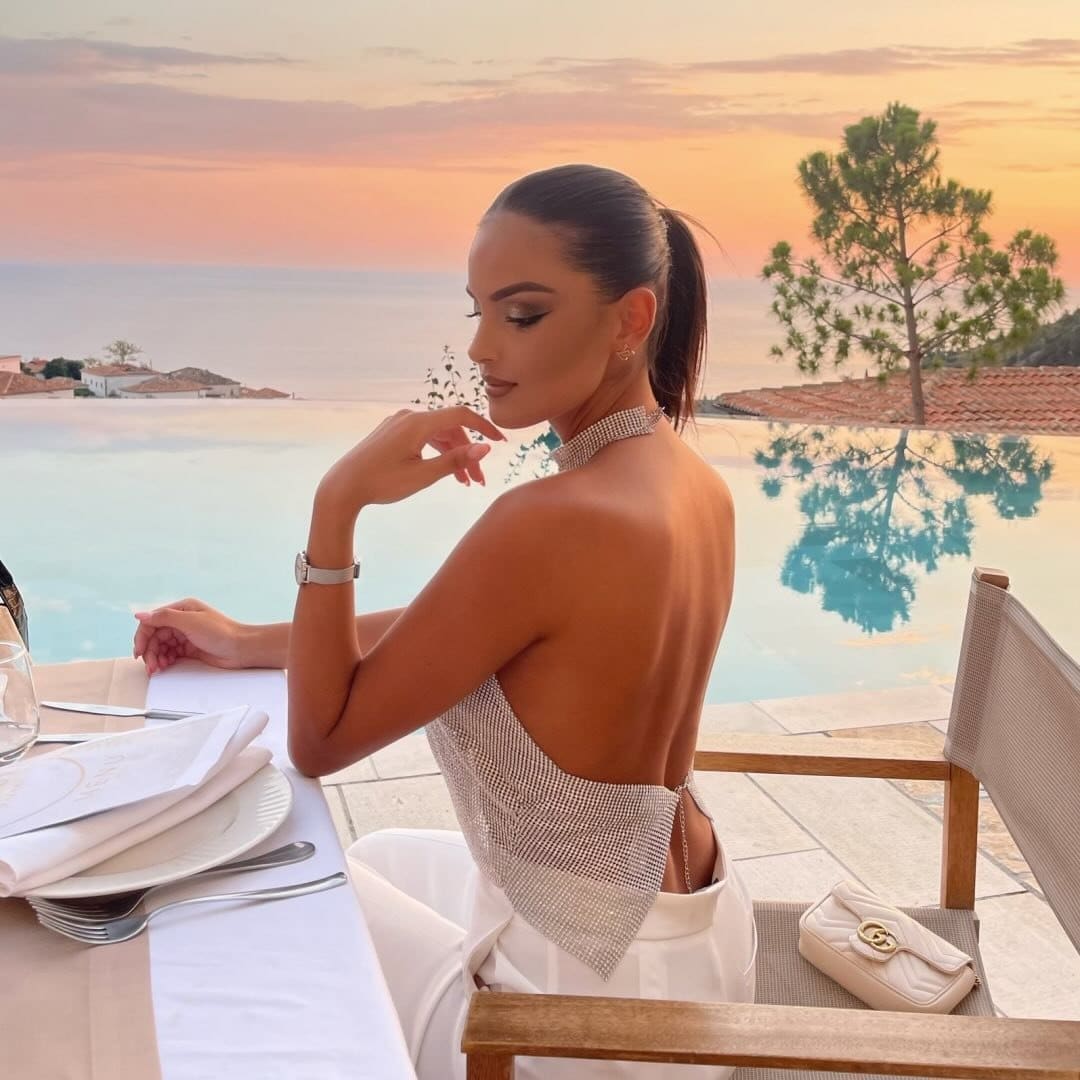 A woman sitting at a table next to a pool.