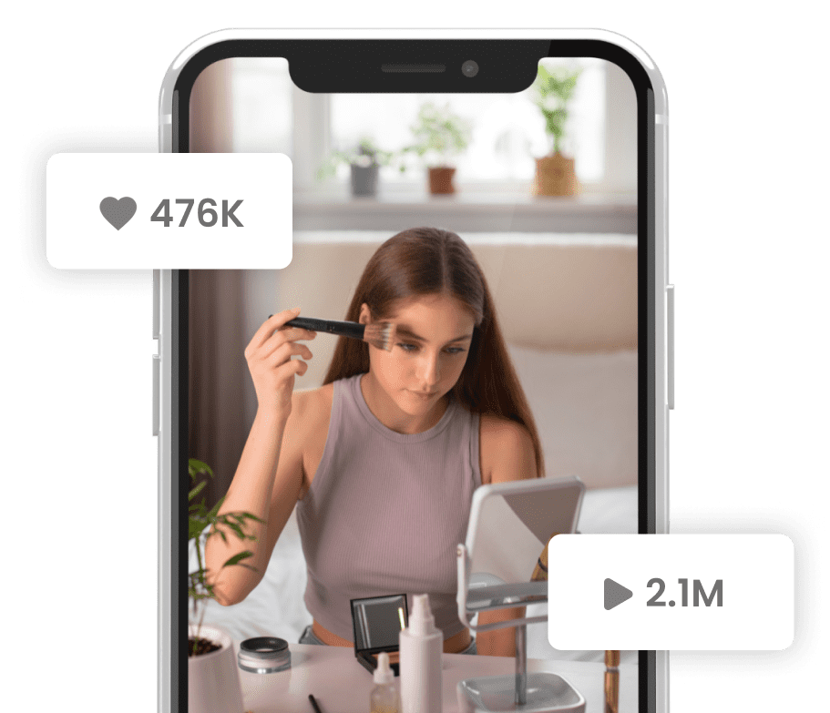 A person is applying makeup in front of a mirror, shown on a smartphone screen. The video has 2.1 million views and 476,000 likes.